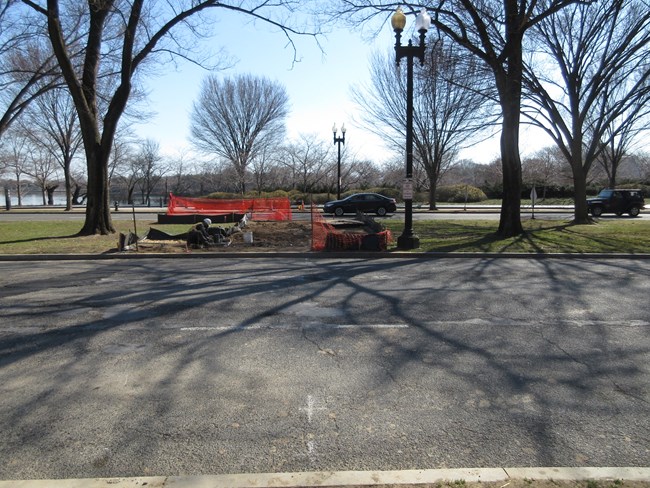 A construction worker installs wires in the ground at the site of a new crosswalk between the MLK Jr Memorial and DC War Memorial on Independence Avenue SW