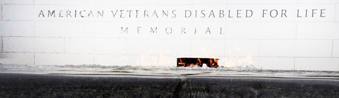 Waves of heat from the ceremonial flame rise from the reflecting pool in front of the white granite Memorial wall.