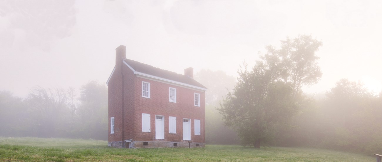 Gordon House is made of brick. Front of house has two white doors and six windows with white window frames.