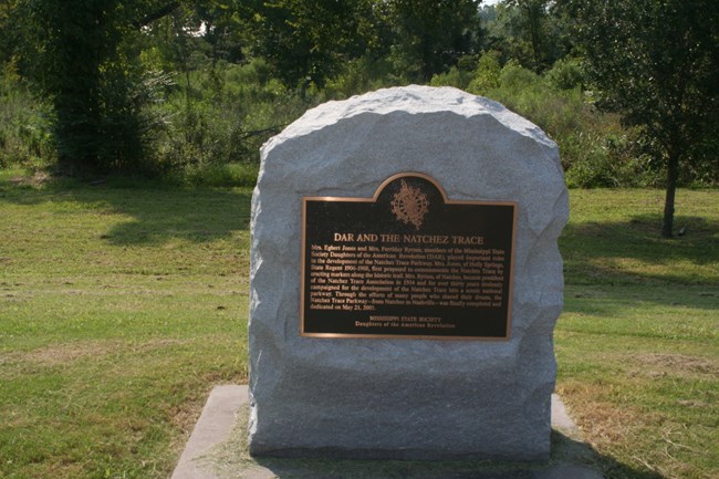 A stone monument with a brass plate with test about the site.