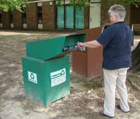 A visitor recycling a plastic bottle in a green recycling bin.