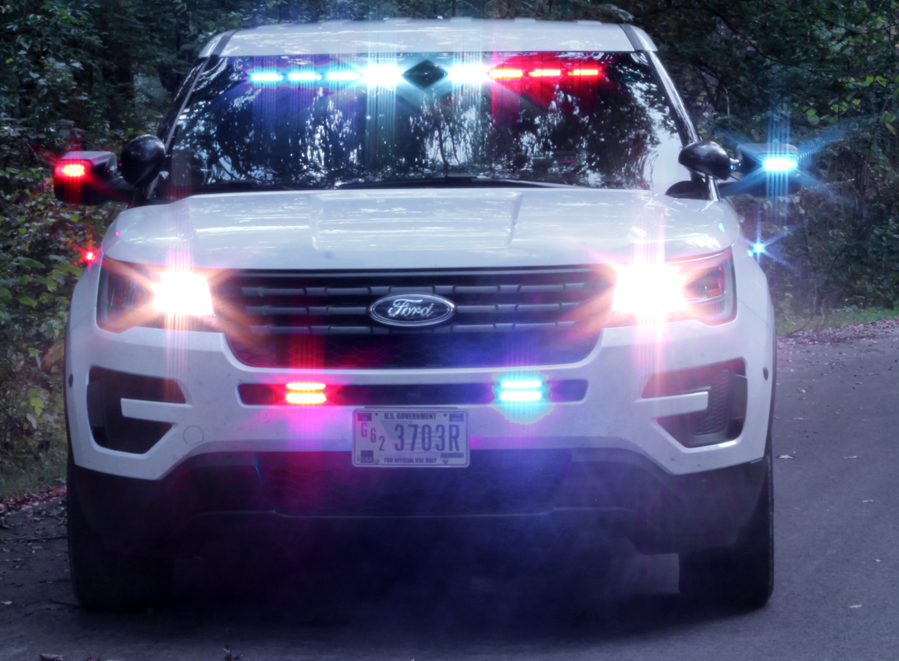 Front end of white patrol vehicle with emergency lights on