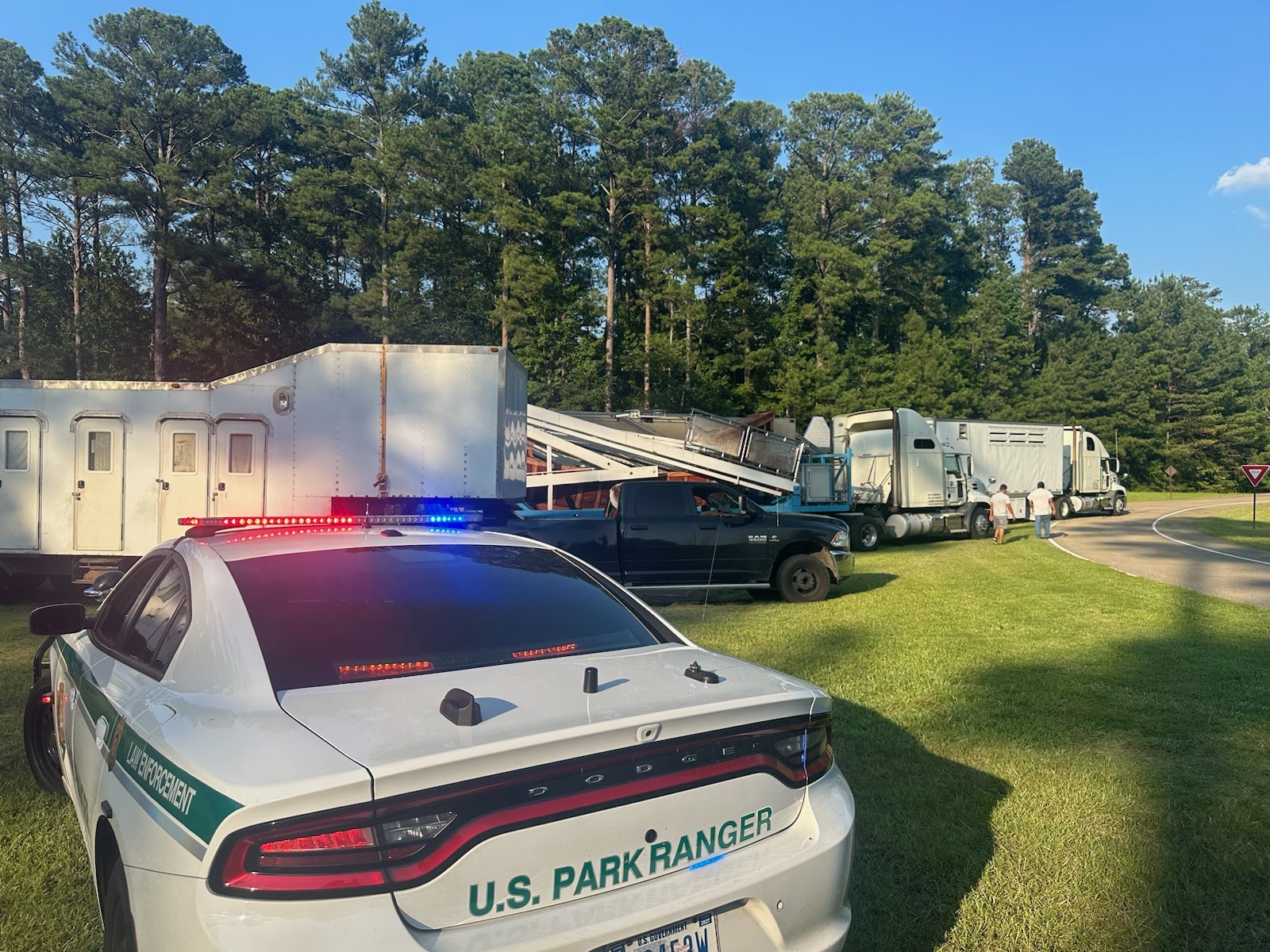 Park Ranger Vehicle close to camera, while 3 large commercial vehicles are stopped further back.