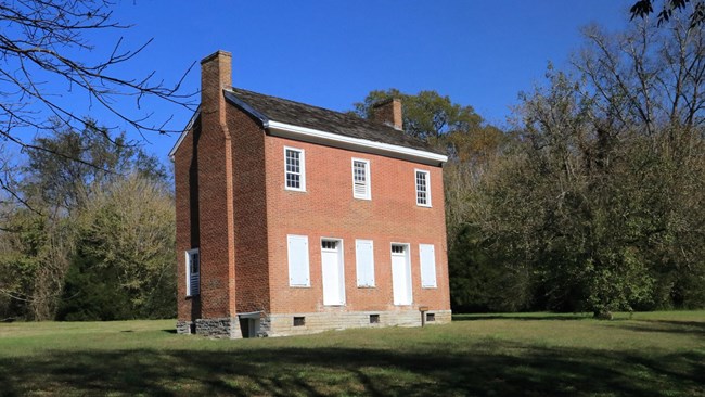 Two story brick building with the doors and windows boarded up.