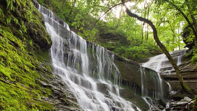 Wide cascading waterfall over fractured rock.