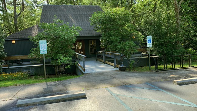 A single story, wood-sided building accessed by a small moat-like walkway.