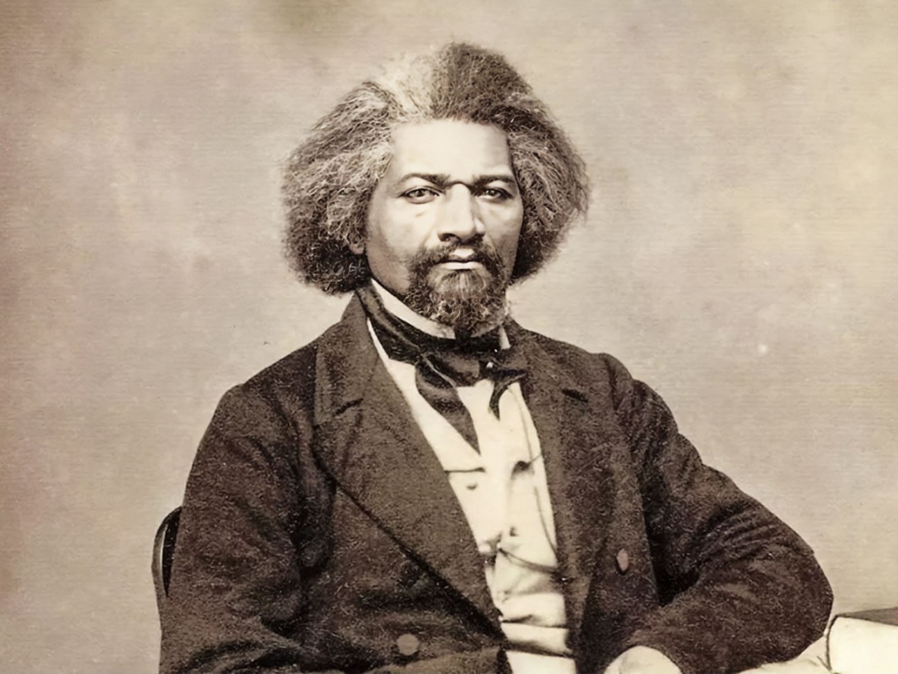 Abolitionist Frederick Douglass sits at a table in 1863.