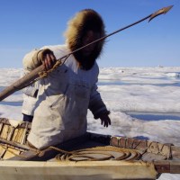An Iñupiat whaleman holds out a harpoon.