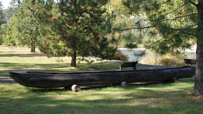 wooden canoe in grass by river