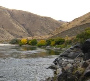 A river surrounded by rocks and hillsides filled with sagebrush.