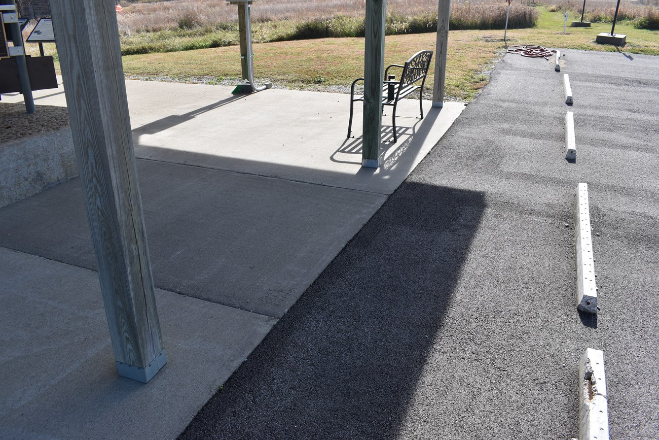 An asphalt parking lot surface joins the edge of a concrete floor.
