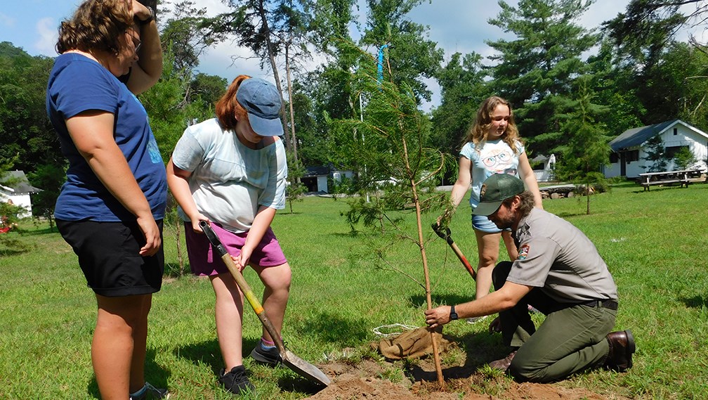 kids and ranger planting a tree