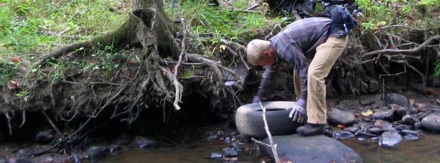 volunteer pulling a tire out of a stream