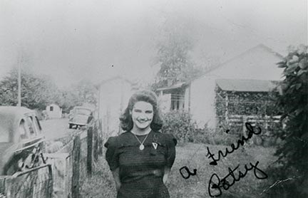 historic photo of a woman standing in front of a house and car