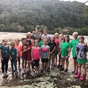 Girl Scouts and ranger pose alongside river