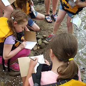 Girl Scouts examining sediment in river