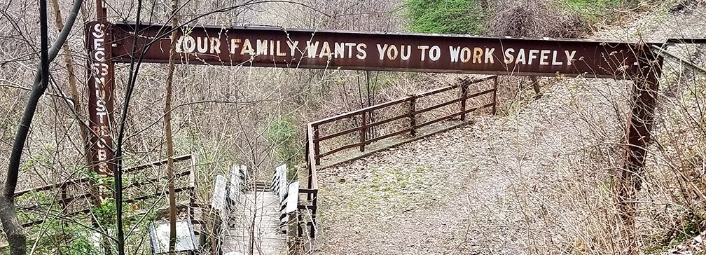 old coal mine safety sign over trail