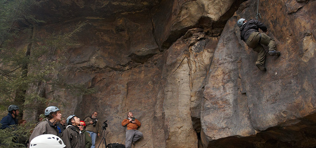 Rock Climbers watch as one climber scales a cliff
