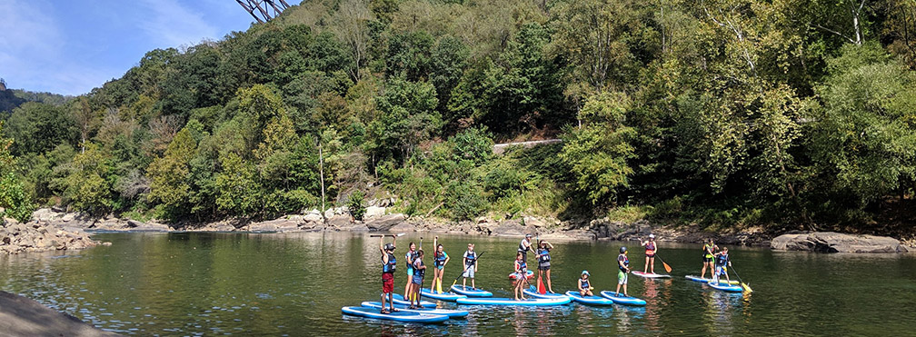 kids standing on paddle boards on river
