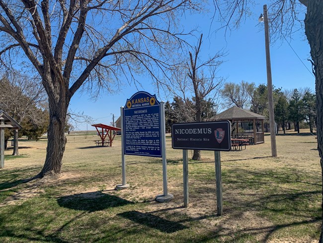 A park with signs and picnic tables.
