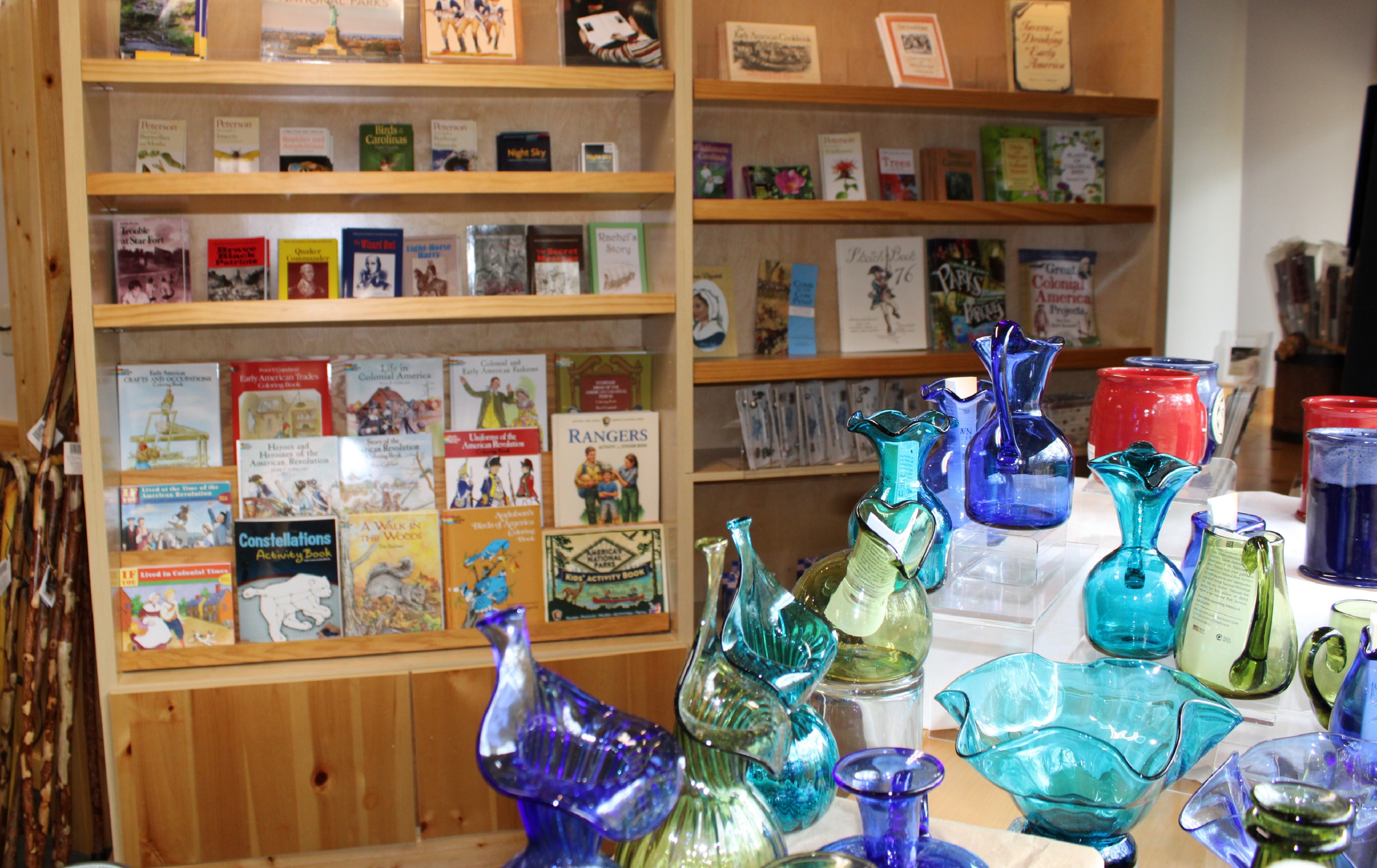 Colorful colonial glassware in front of a shelf of books.