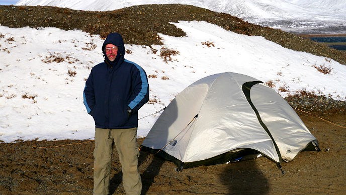 Man standing in front of tent with snow on the grond