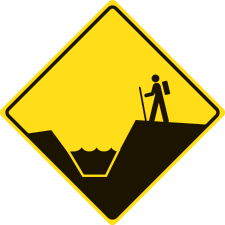 Diamond shaped yellow warning sign with a hiker above a drainage