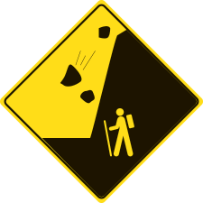 A yellow diamond sign with falling rocks above a hiker