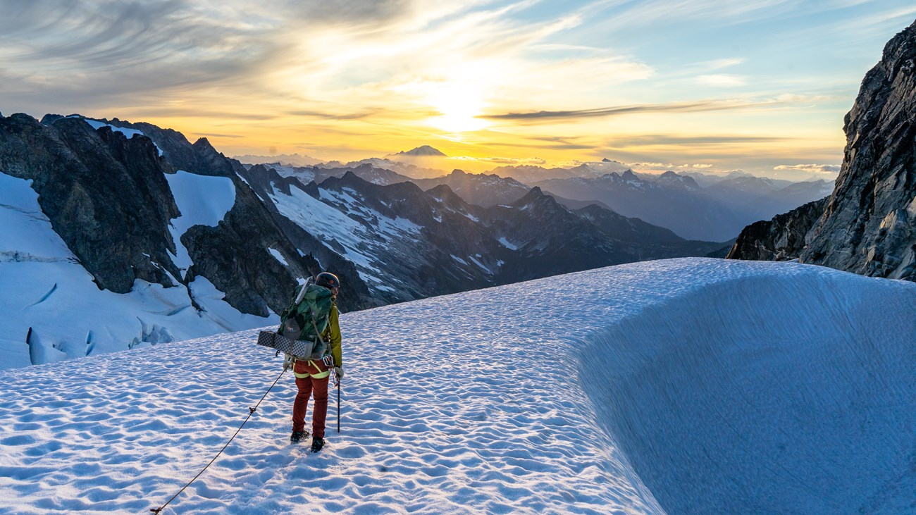 A climber travels on snow at sunset