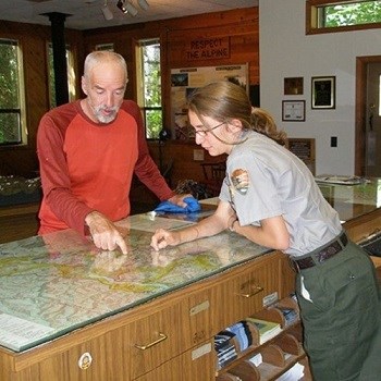 A ranger and park visitor look at a map on the counter.