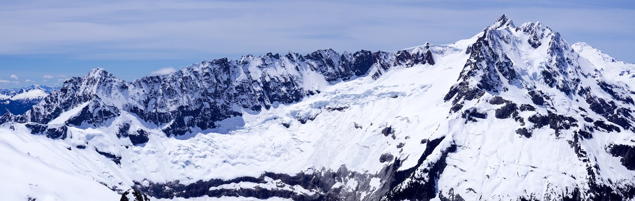 Steep and snowy mountains and ridges with a large broken glacier
