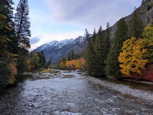 Snowy mountain above a river in fall