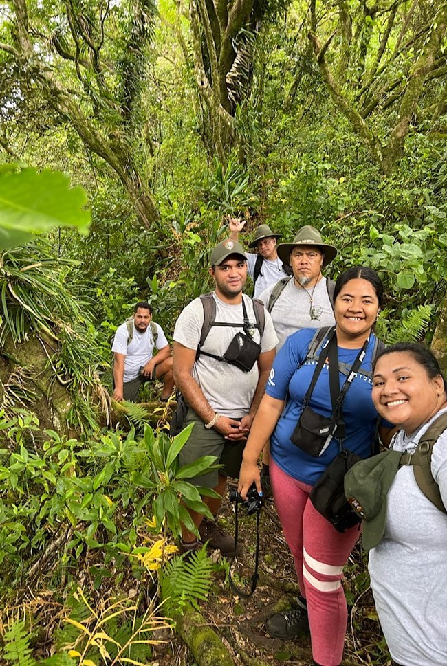 A group of men and women on a trail. They are smiling at the camera.