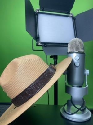 A NPS ranger hat leaning up against a free-standing microphone. There is a greenscreen and studio light in the background.