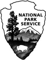Black and white arrowhead logo, point down. At top right, black text, National Park Service. At left, a tall tree. At bottom, a white bison stands on a field ending in a distant tree line, a white lake at right. A snow-capped mountain towers behind.