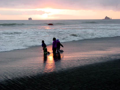Three kids playing at sunset on a sandy beach