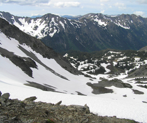A mountain view as seen from Cameron Pass. A snowy basin lies below, and a snowy mountain ridge rises in the background.