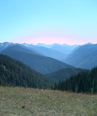 A view of sky mountains from atop a mountain meadow during the summer