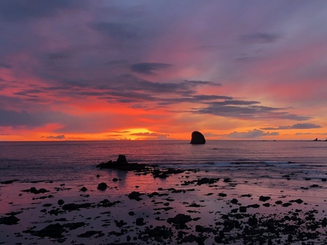 Sunset on coastal horizon with seastacks in the distance.