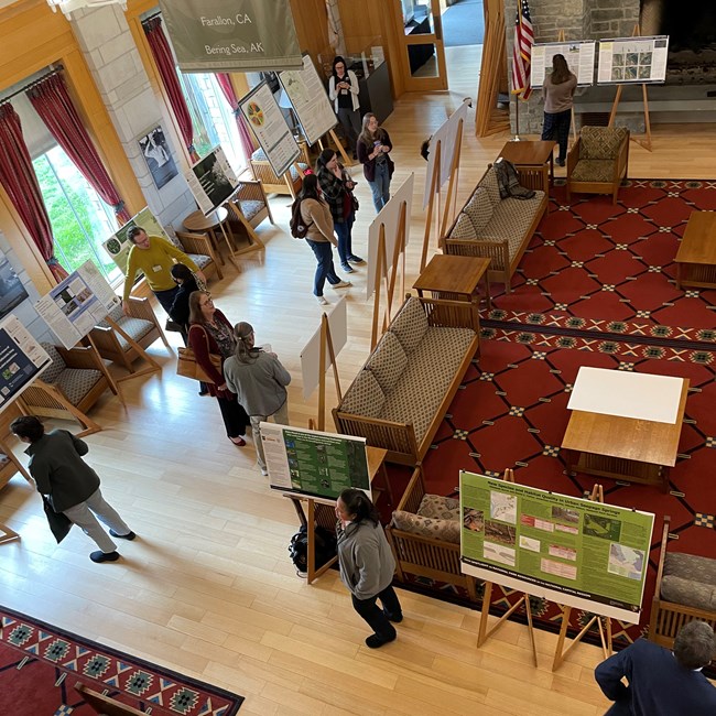 Looking down from above as people discuss posters in a hotel lobby like setting