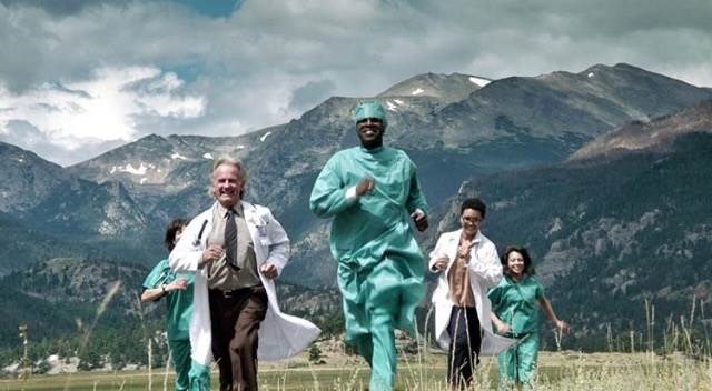 Group of doctors in surgical gowns running with mountains in the background.