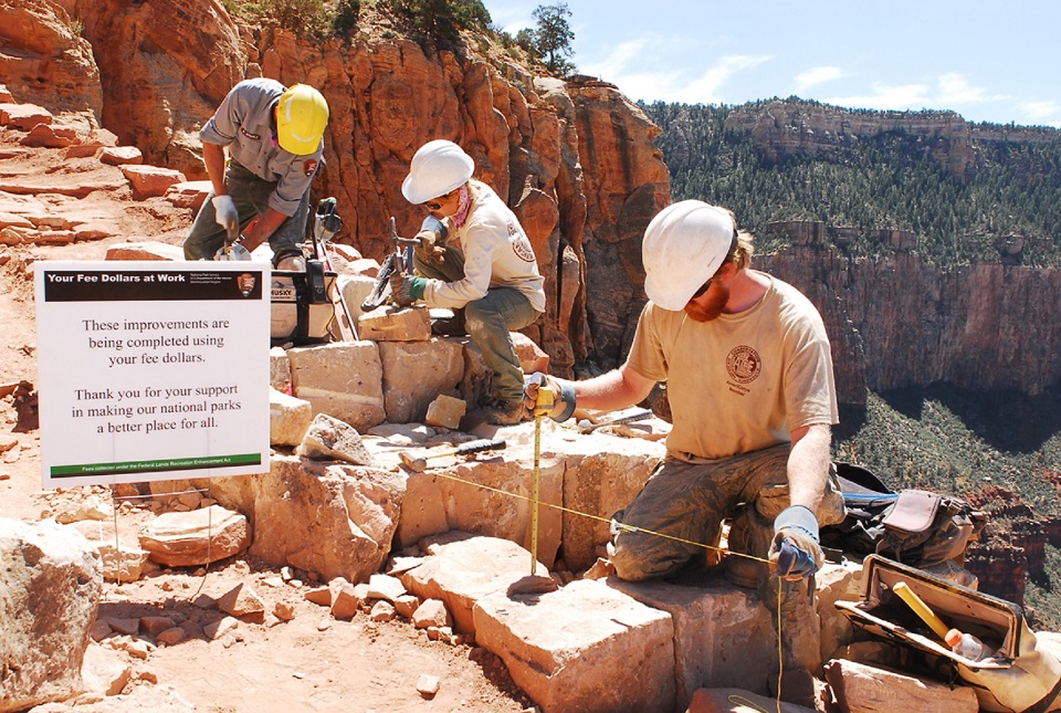 Three employees or volunteers working on a section of trail in the Grand Canyon