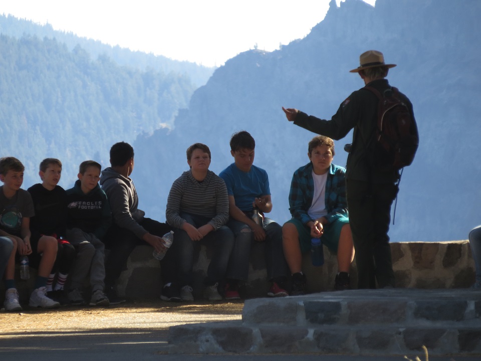 Ranger giving a talk to youth seated on a stone wall