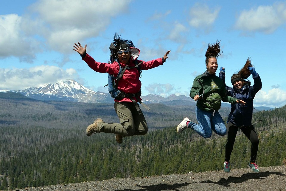 Three people jumping with mountains in background