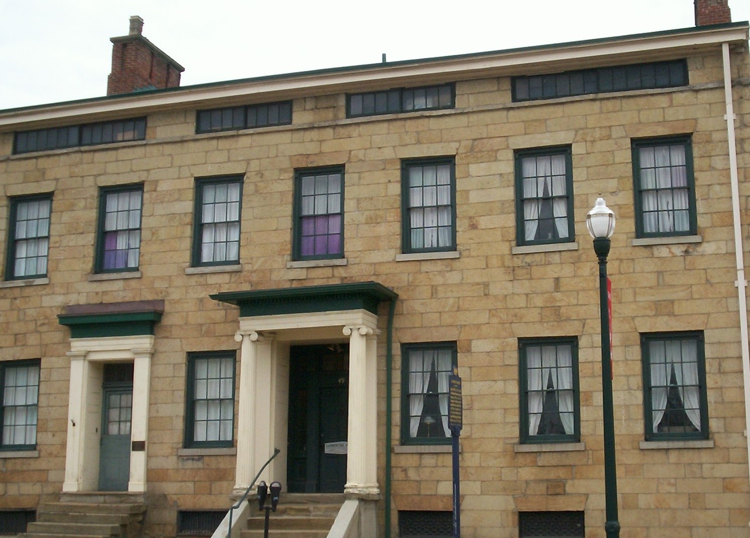Two and a half story brown stone building with two front doors and multiple windows.
