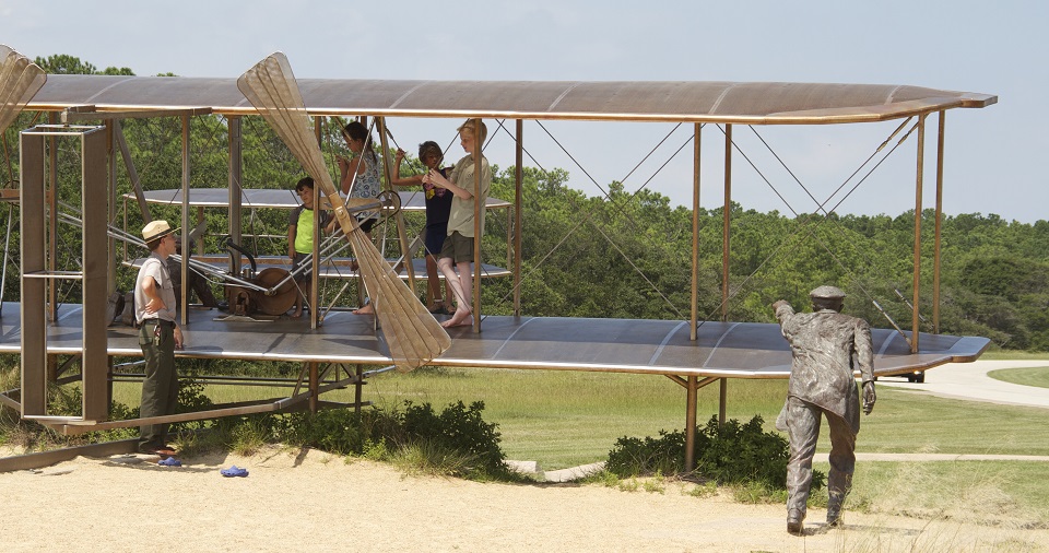 Kids playing on a bronze statue of a historic airplane