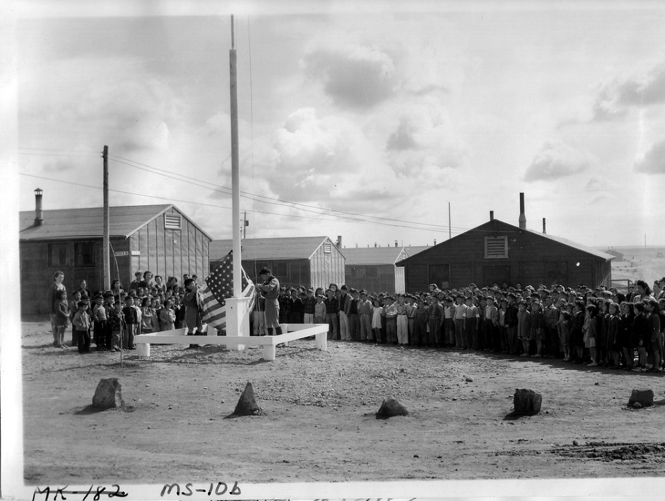 Historical black and white photo of incarcerated Japanese American children in front of a school building