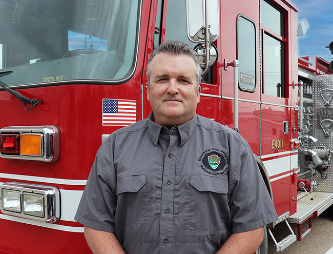 A person stands in front of a fire engine.