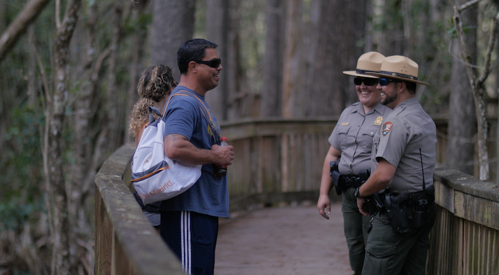 Two law enforcement rangers having a conversation with two park visitors.