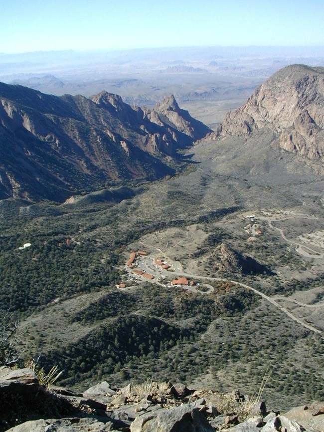 An aerial view of a visitor’s center in a valley surrounded by high peaks.